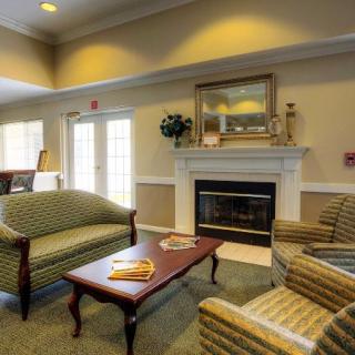 Cozy living room with a fireplace, sofas, and armchairs arranged around a coffee table.