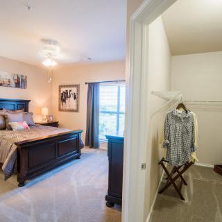 A cozy bedroom with a view into a walk-in closet, featuring elegant furniture and tasteful decorations.