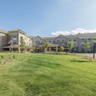 A modern residential building with a well-maintained lawn under a clear blue sky.