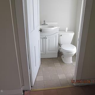 A small bathroom with a toilet and sink, featuring white walls and a minimalist design.
