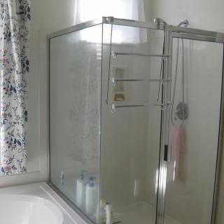 A clean bathroom featuring a glass shower enclosure and a bathtub with a curtain.