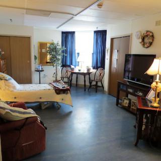 A cozy and well-furnished room featuring a bed, seating area, and a dining table.