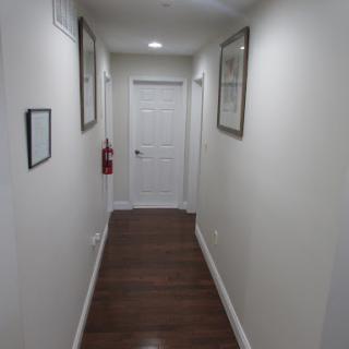 A well-lit hallway featuring framed pictures on the walls, leading to a closed door.