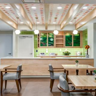 A modern restaurant interior featuring wooden tables, stylish chairs, and a bright, inviting atmosphere with green accent walls.