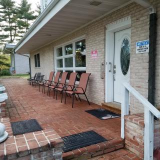 A cozy porch with multiple chairs lined up along a brick walkway.