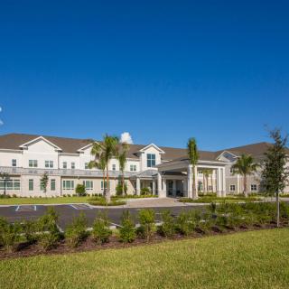 A modern residential building surrounded by greenery under a clear blue sky.