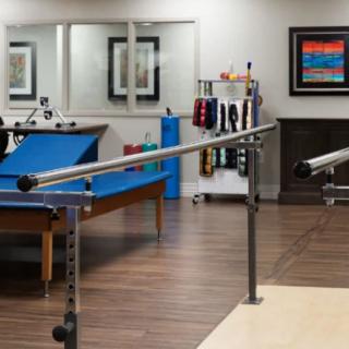 A physical therapy clinic with parallel bars and various equipment.
