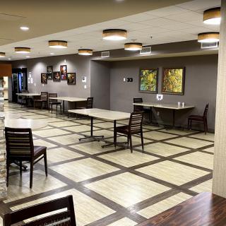 An empty dining area with neatly arranged tables and chairs, decorative lighting, and wall art.