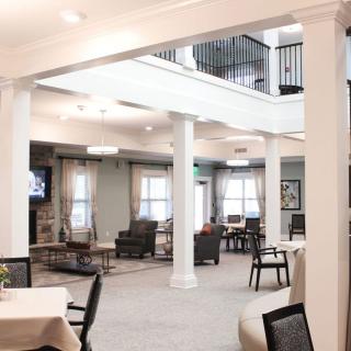 A spacious interior with comfortable seating areas and dining tables, featuring elegant columns and bright lighting.