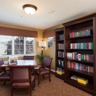 Cozy reading room with a table, chairs, and a well-stocked bookshelf.