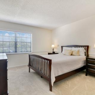 A bright and cozy bedroom with a wooden bed frame, dresser, and nightstands.