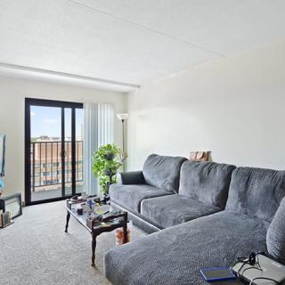 A bright and cozy living room with a comfortable sofa, coffee table, and access to a balcony.