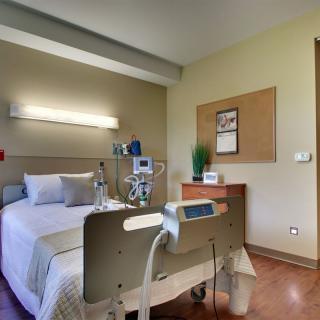A hospital room featuring a bed equipped with medical devices and essential amenities.