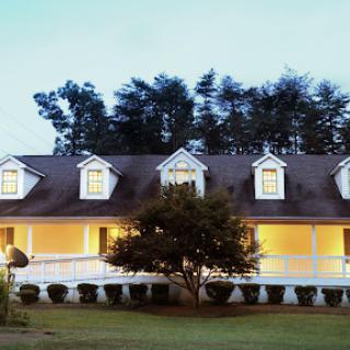 A charming residential house illuminated in the evening, surrounded by trees.