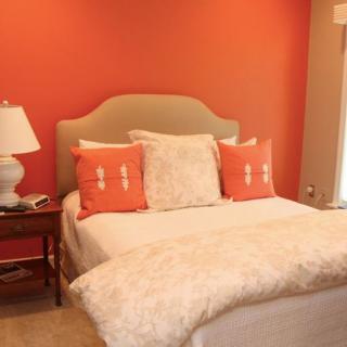 A cozy bedroom with vibrant orange walls and a neatly made bed.