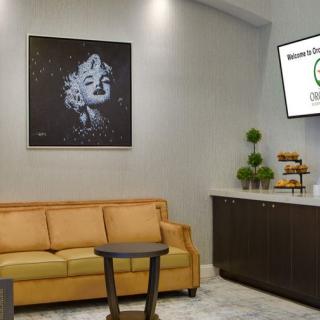 A modern lobby area with a comfortable sofa, stylish artwork, and a television screen, creating an inviting atmosphere.