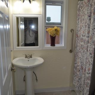 A small bathroom with a pedestal sink, mirror, and shower curtain.