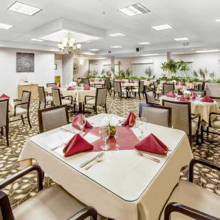 An elegant indoor dining area with neatly arranged tables and red napkins.