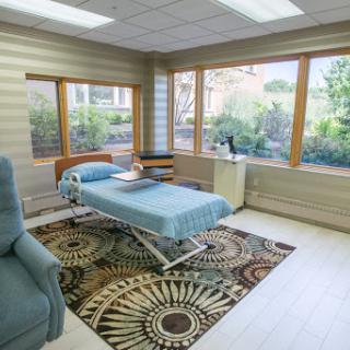 A bright and airy hospital room designed for patient comfort, featuring large windows and modern furnishings.