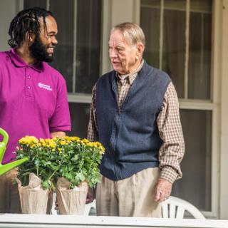A warm interaction between two individuals tending to flowers on a porch.