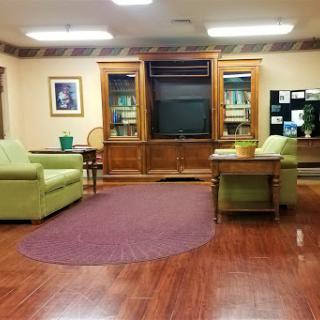 A cozy lounge area featuring green chairs, a television, and wooden cabinets.