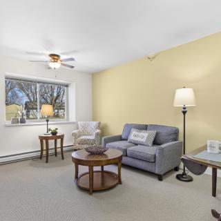 A cozy living room with a sofa, armchair, and coffee table, featuring soft lighting from a floor lamp.