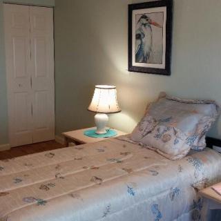 A cozy bedroom with a single bed, nightstand, and lamp.