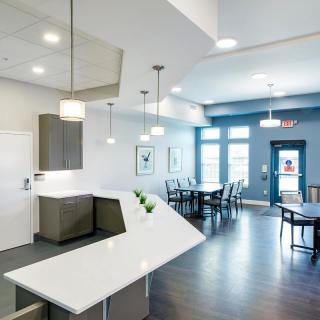 A modern open-plan kitchen and dining area with sleek white countertops and pendant lighting.