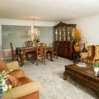 A cozy living and dining area featuring classic wooden furniture, a chandelier, and decorative accents.