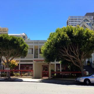 A street view with trees, cars, and buildings on a sunny day.