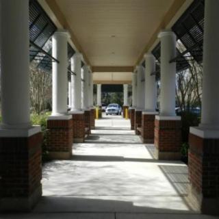 A sunlit corridor with columns casting shadows along the walkway.