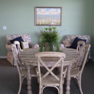 A cozy dining area with a round wooden table, cushioned chairs, and stylish decor in soft colors.