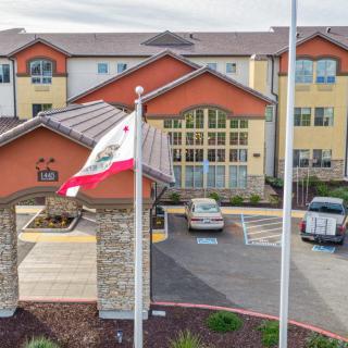 A hotel exterior with a parking lot and flags at the entrance.