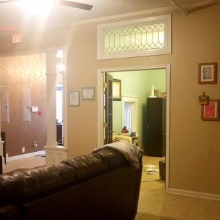 A cozy living room with a sofa, warm lighting, and decorative wall art, leading into another room.