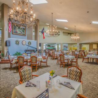 A spacious dining area with chandeliers, elegantly set tables, and a formal atmosphere.