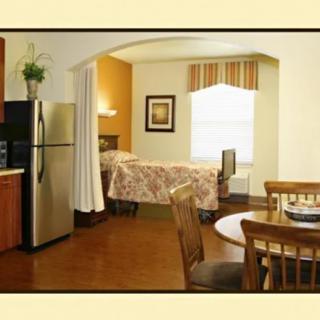 A cozy studio apartment with an open layout featuring a kitchen, bedroom, and dining area.
