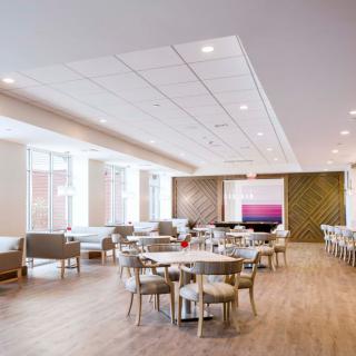 A modern lounge with tables and chairs, featuring bright lighting and a spacious design.