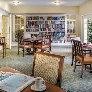 A cozy reading area with bookshelves, tables, and chairs.