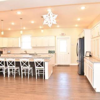 A spacious modern kitchen with white cabinets, a large island, and pendant lighting.