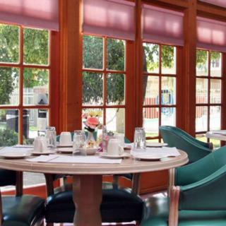 A beautifully set dining table in a restaurant with large windows letting in natural light.