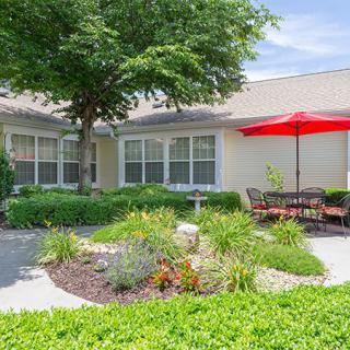 A well-maintained garden patio with outdoor seating and a red umbrella.