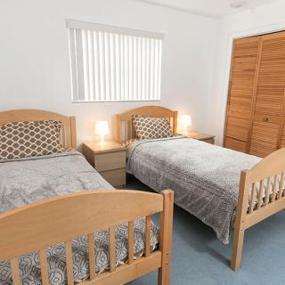 A cozy bedroom with two wooden twin beds and a shared nightstand with lamps.