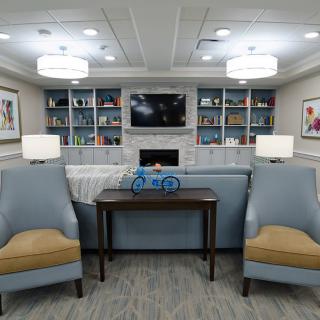 A cozy living room with comfortable seating, bookshelves, and ambient lighting.