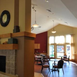 A cozy interior featuring a fireplace, dining tables, and large windows allowing natural light.