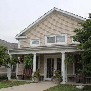 A charming residential house with a welcoming porch and greenery.