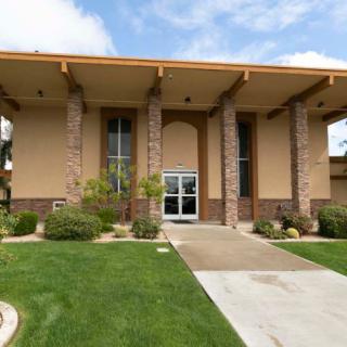 A modern building with large columns and well-maintained landscaping under a partly cloudy sky.