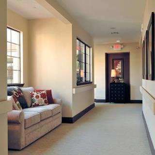 A cozy hallway with a couch by the windows, featuring soft lighting and decorative pillows.