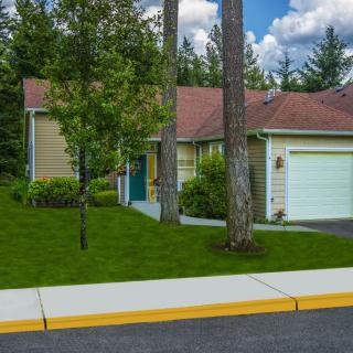 A suburban house with a garage and well-maintained lawn surrounded by trees.