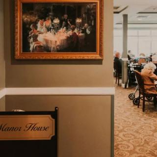 A cozy restaurant interior with a framed painting and diners enjoying their meals.