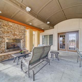A cozy outdoor patio with comfortable seating and a stone fireplace under a covered roof.